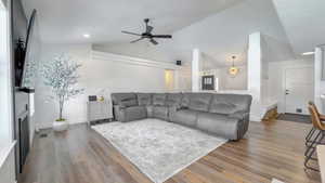 Living area featuring vaulted ceiling, light wood-type flooring, a ceiling fan, and a large fireplace