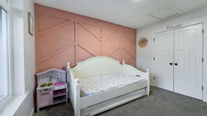 Bedroom with attic access, dark colored carpet, and a closet