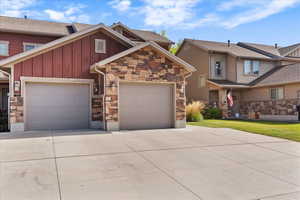 Craftsman-style house featuring board and batten siding, concrete driveway, stone siding, and a garage