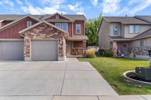 Craftsman-style house with a front lawn, board and batten siding, driveway, and stone siding