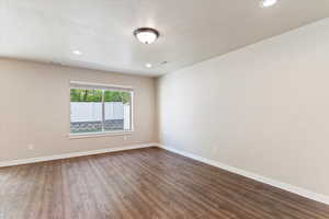 Spare room featuring dark wood-type flooring, recessed lighting, and a textured ceiling
