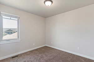 Carpeted spare room featuring baseboards