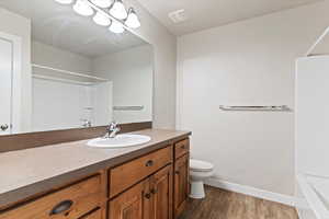 Full bathroom with dark wood-style floors, vanity, and  shower combination