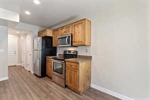 Kitchen with appliances with stainless steel finishes, dark wood-type flooring, recessed lighting, and dark countertops