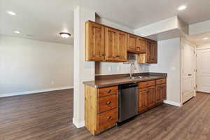 Kitchen with recessed lighting, dark countertops, brown cabinetry, dark wood finished floors, and dishwasher