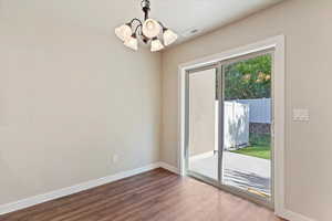 Unfurnished dining area with a chandelier and dark wood-type flooring
