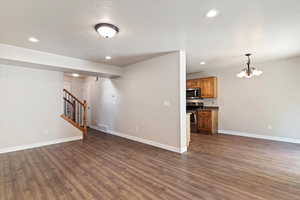 Unfurnished living room with stairway, recessed lighting, a chandelier, dark wood-style flooring, and a textured ceiling
