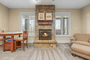 Carpeted living room featuring a stone fireplace and healthy amount of natural light