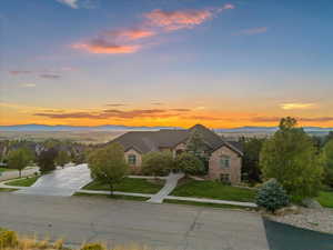 View of front facade featuring a mountain view, brick siding, driveway, and a front lawn