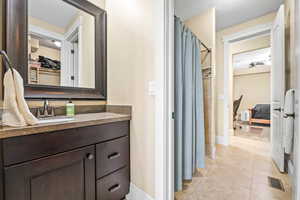 Ensuite bathroom with a shower with curtain, vanity, a textured ceiling, and light tile patterned flooring