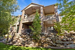 Rear view of house with ceiling fan, brick siding, and a balcony