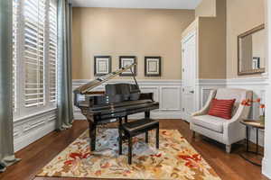 Living area featuring a wainscoted wall, a decorative wall, and dark wood-style flooring