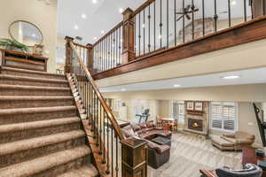 Staircase with a high ceiling, recessed lighting, a fireplace, carpet floors, and ceiling fan