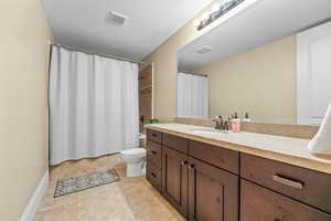 Bathroom featuring shower / bathtub combination with curtain, vanity, a textured ceiling, and light tile patterned flooring