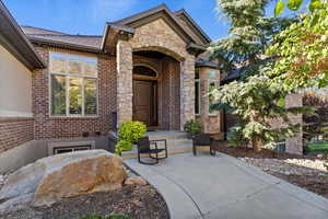 View of exterior entry with stone siding and brick siding