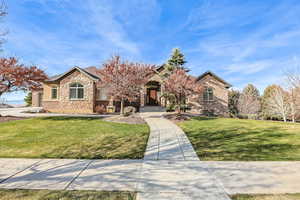 View of front of property with a front lawn, stone siding, and brick siding