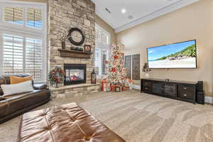 Carpeted living area featuring a fireplace and crown molding