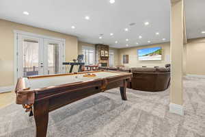 Rec room featuring recessed lighting, pool table, french doors, light colored carpet, and a stone fireplace