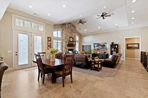 Dining area featuring a stone fireplace, high vaulted ceiling, recessed lighting, a ceiling fan, and ornamental molding