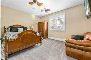 Carpeted bedroom with ceiling fan and baseboards