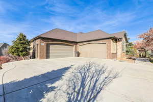 View of front of house with a shingled roof, brick siding, concrete driveway, and a garage
