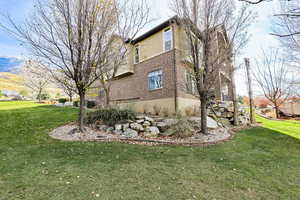 View of home's exterior with brick siding, a lawn, and stucco siding
