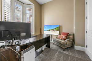 Office area featuring dark colored carpet and baseboards