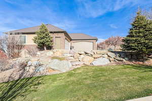 View of side of home featuring brick siding, a yard, and an attached garage