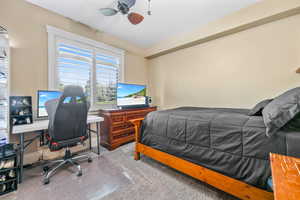 Carpeted bedroom featuring a desk and ceiling fan