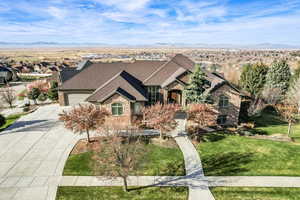 French country home featuring driveway, brick siding, a front yard, a mountain view, and an attached garage