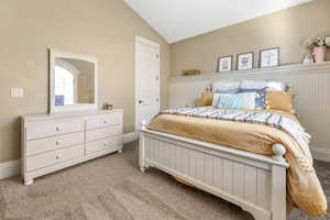 Bedroom with vaulted ceiling and light carpet