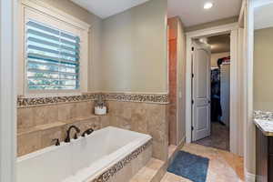 Bathroom with vanity, a garden tub, a spacious closet, light tile patterned floors, and a stall shower