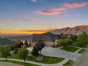 View of front of property featuring concrete driveway, a garage, a mountain view, a lawn, and brick siding