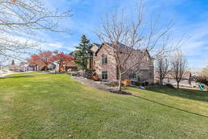 View of side of home featuring a lawn and brick siding