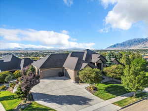 View of front of house with an attached garage, concrete driveway, a mountain view, brick siding, and a front lawn