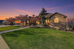View of front of property featuring stone siding and a front lawn