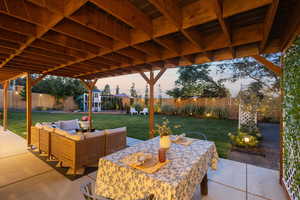 Patio terrace at dusk with a fenced backyard, a patio, outdoor lounge area, and a playground