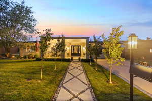 View of front of property featuring a lawn, french doors, and stucco siding