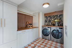 Laundry area with separate washer and dryer, light flooring, and cabinet space
