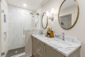 Full bath with double vanity and a shower stall