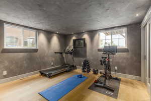 Exercise room with light wood-style flooring and recessed lighting