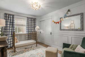 Bedroom featuring wood finished floors, a nursery area, and a closet