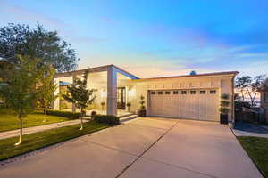 View of front of property featuring concrete driveway, an attached garage, and a front lawn