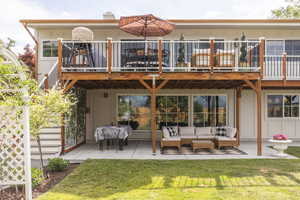 Rear view of house with a patio, board and batten siding, a lawn, and an outdoor hangout area