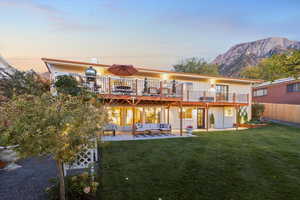 Back of house with a patio area, an outdoor living space, and a deck with mountain view