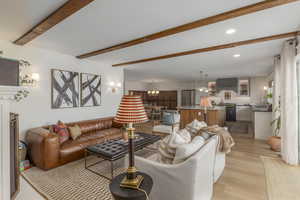 Living room featuring a chandelier, recessed lighting, beam ceiling, and light wood finished floors