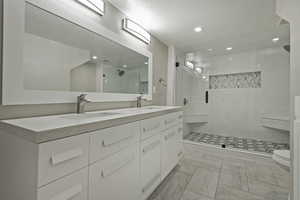 Bathroom featuring a stall shower, double vanity, a textured ceiling, and recessed lighting