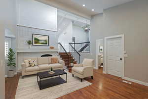 Living room with high vaulted ceiling, dark wood finished floors, stairs, a chandelier, and recessed lighting