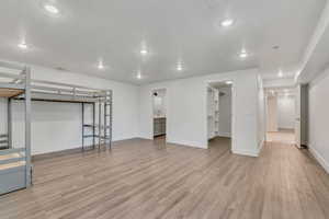 Finished basement with light wood-style flooring and recessed lighting