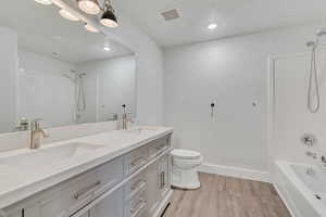 Full bath with shower / washtub combination, light wood-style floors, double vanity, and recessed lighting
